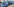 Sechs Frauen in hellblauen Burkas sitzen auf einem Stapel aus Metallstangen