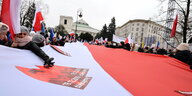Menschen demonstrieren vor dem Parlament mit einer riesigen, weiß-roten Polenflagge gegen das neue Mediengesetz der rechtsnationalen Regierung