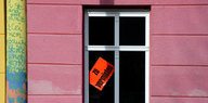 Im Fenster eines Hauses mit rosa gestrichener Fassade steckt ein roter Zettel: Zu vermieten steht darauf