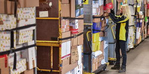Eine Mitarbeiterin überprüft die Ladung an einem Transportwagen für Pakete im DHL-Paketzentrum in Rüdersdorf