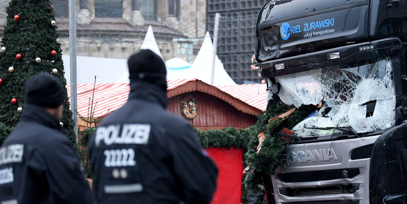 ein zerstörter Lkw, Polizisten im Vordergrund