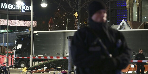 Ein Polizist bewacht die Absperrung am Breitscheidplatz bei Nacht. Im Hintergrund ein Schriftzug der Morgenpost
