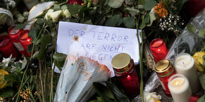 Zwischen Kerzen und Blumen steht ein Schild, auf dem steht „Wir lieben Berlin“