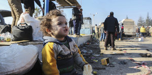 Ein kleines Kind sitzt, aus Aleppo evakuiert, in einem Flüchtlingscamp nahe Idlib