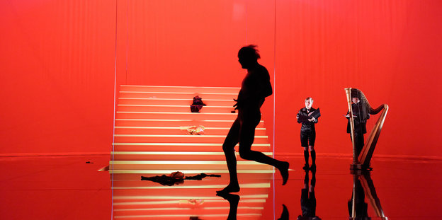 Ein nackter Mann rennt über eine rote Bühne