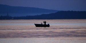 Ein Fischer auf einem Boot im letzten Licht des Tages