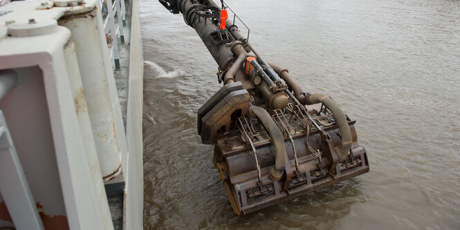 Ein Schiffsbagger hat seine Schaufel ins Wasser eingetaucht