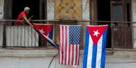 Ein Mann schmückt seinen Balkon mit der kubanischen und der US-Flagge