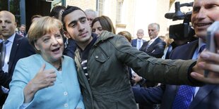 Anas Modamani und Angela Merkel machen ein Foto im September 2015