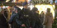 Ein Polizist steht vor einer Menge Menschen und weihnachtlicher Dekoration