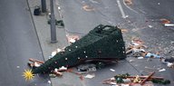 Ein Weihnachtsbaum liegt umgekippt auf einer Straße, daneben Müll