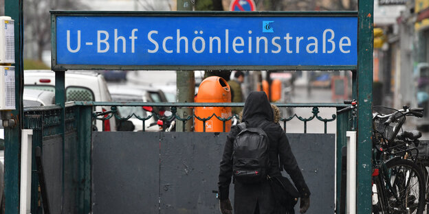 Eine Frau in schwarzer Jacke geht die Treppe zum U-Bahnhof Schönleinstraße hinunter