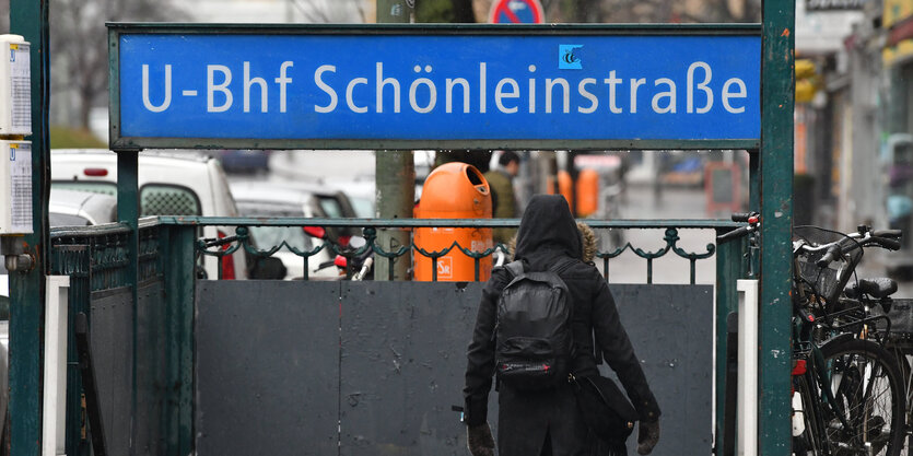 Eine Frau in schwarzer Jacke geht die Treppe zum U-Bahnhof Schönleinstraße hinunter