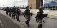 Neun paramilitärisch ausgerüstete Polizisten gehen hintereinender vor dem Silviri-Gefängnis entlang