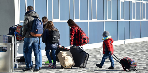 Eine Familie betritt mit Koffern einen Flughafen
