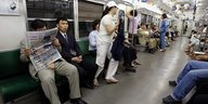 Einige Menschen in einer U-Bahn, einige sitzen, andere stehen