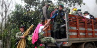 Mehrere Männer, teilweise uniformiert, steigen auf die Ladefläche eines Lastwagens