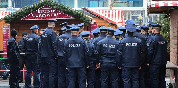 Eine Gruppe Polizisten vor einer Weihnachtsmarktbude