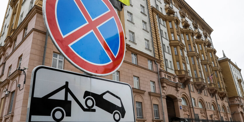 Vor einem Gebäude steht ein Schild, das ein Parkverbot anzeigt und das Abschleppen von Autos androht