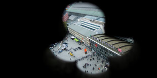 Durch eine Auslassung in einer Dommauer blickt man auf den Hauptbahnhof