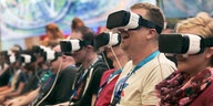 Menschen sitzen in einer Reihe und tragen VR-Brillen