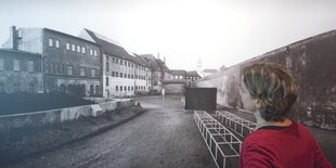 Eine Frau steht vor einem Foto der Gedenkstätte Torgau