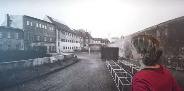 Eine Frau steht vor einem Foto der Gedenkstätte Torgau