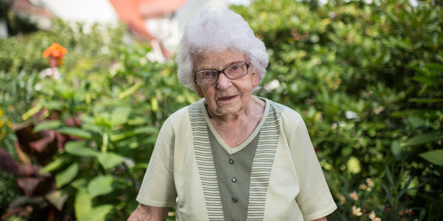 Eine ältere Dame steht in einem Garten
