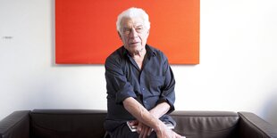 John Berger sitzt im hochgekrempelten Hemd auf einer Couch