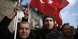 Zwei Männer tragen türkische Flaggen