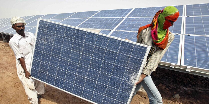 Zwei Männer tragen ein Solarpanel