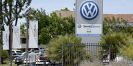 Das Schild einer Einfahrt eines Volkswagen-Verkaufshauses inmitten von mehreren Palmen