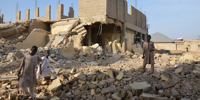 Auf der Ruine einer Grundschule in Zaria stehen Kinder und blicken in die Kamera.