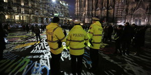 Polizisten in gelben Schutzwesten stehen in der Silvesternacht in Köln vor dem Dom