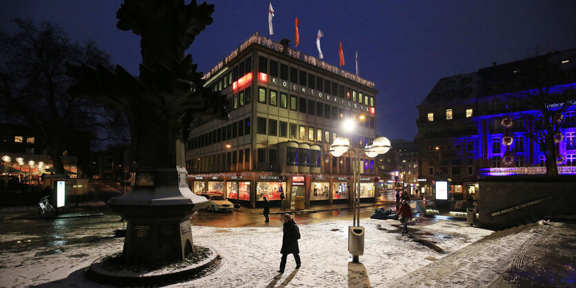 Ein Mensch läuft bei Nacht über einen verschneiten, einsamen Platz