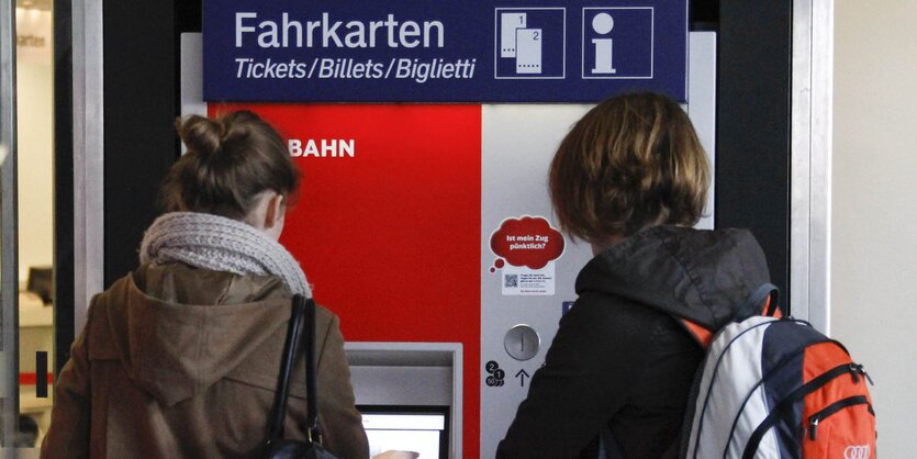 Zwei Fahrgäste wollen ein Ticket am Automaten ziehen