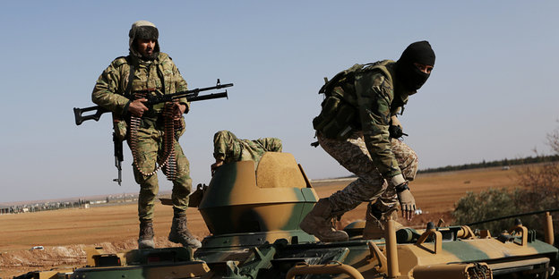 Kämpfer in Tarnkleidung stehen auf einem Militärfahrzeug