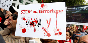Tunesier demonstrieren gegen den Terrorismus mit einem „Stop au terrorisme“-Plakat