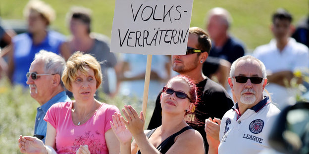 Eine Frau hält ein Schild mit der Aufschrift "Volksverräterin" in einer Menschenmenge