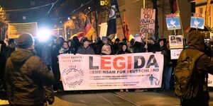 Menschen in einer Demo tragen ein Transparent mit der Aufschrift "Legida"