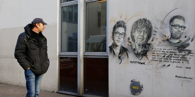 An der Hauswand der ehemaligen Charlie Hebdo Redaktion sind die Gesichter dreier Opfer gezeichnet