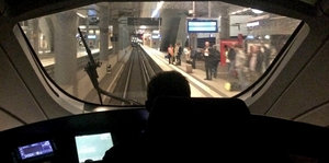 Blick über die Schulter eines Lokführers, während der Zug in den Bahnhof einrollt