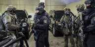 Polizisten mit neuen Waffen vor neuen gepanzerten Fahrzeugen