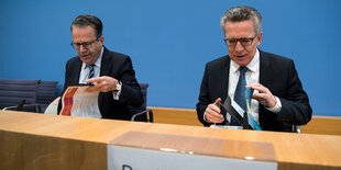 Thomas de Maiziere sitzt mit einem anderen Mann an einem Tisch