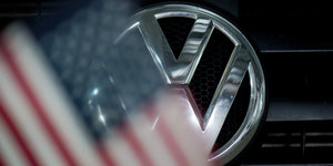 Ein VW-Logo mit davorhängender, unscharfer USA-Flagge