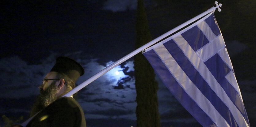 ein christlich-orthodoxer Priester mit griechischer Flagge in Genf