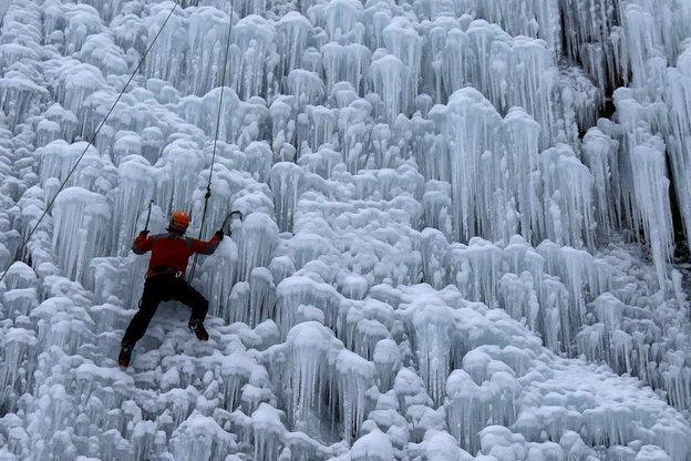 Ein Mann klettert eine künstliche Wand mit Eiskristallen empor