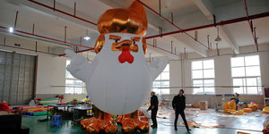 Ein großes aufblasbares Huhn, das Ähnlichkeiten mit Donald Trump hat, steht in einer Halle