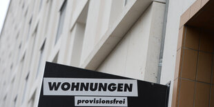 An einer Hauswand hängt ein Schild, das provisionsfreie Wohnungen anpreist