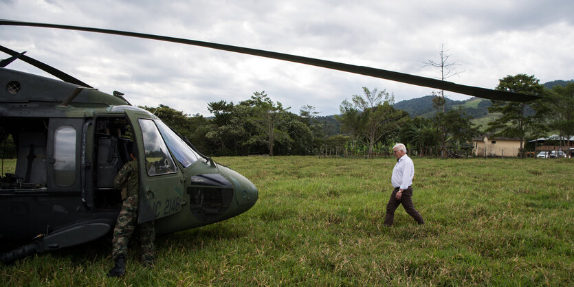 Ein Mann auf einer Wiese geht auf einen Militärhubschrauber zu